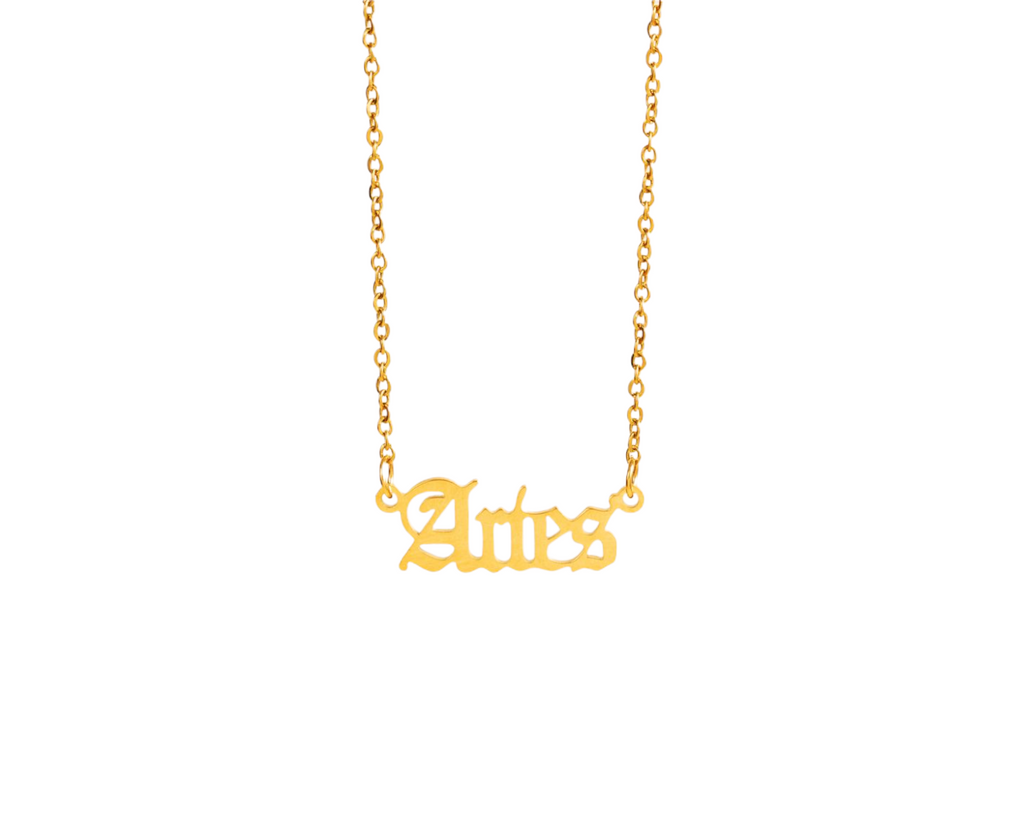 Close-up of a gold necklace featuring the word ‘Aries’ in a stylish, script font, designed for zodiac jewelry lovers.