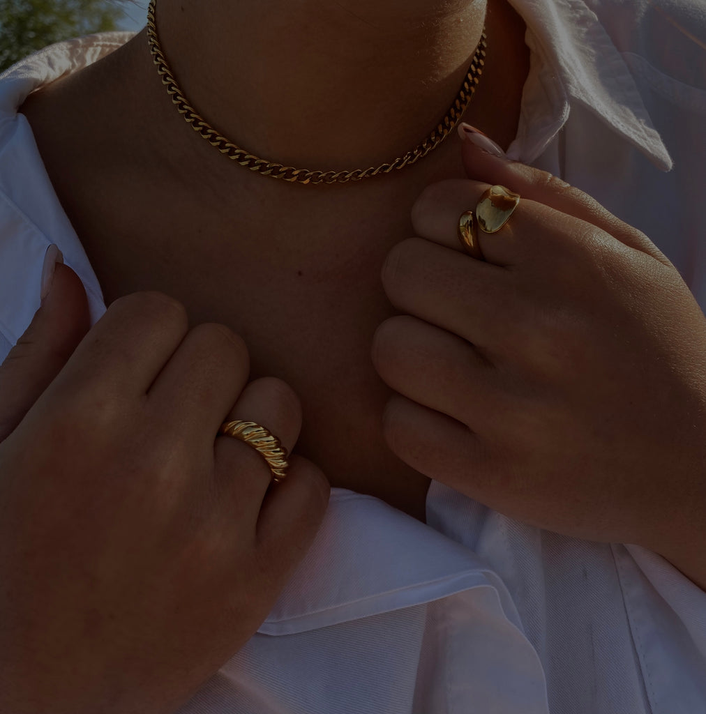 Gold croissant ring being modeled on a finger, showcasing its smooth, curved design and polished finish in a close-up view.