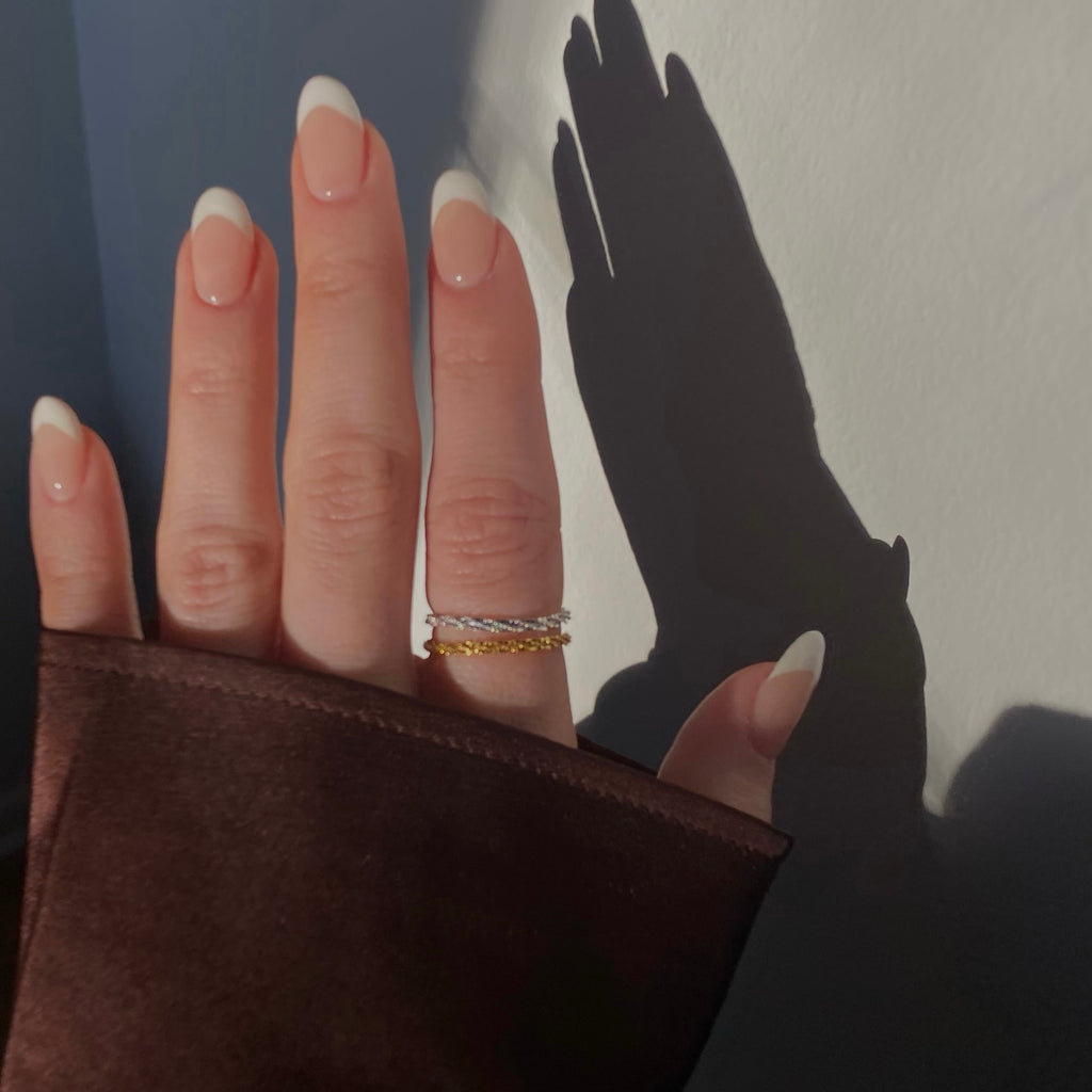 Here's an alt text for an image featuring both a dainty gold and a dainty silver Two dainty rings displayed together: a delicate gold ring with a polished finish and a minimalist design, and a matching dainty silver ring with a similar refined, polished appearance.